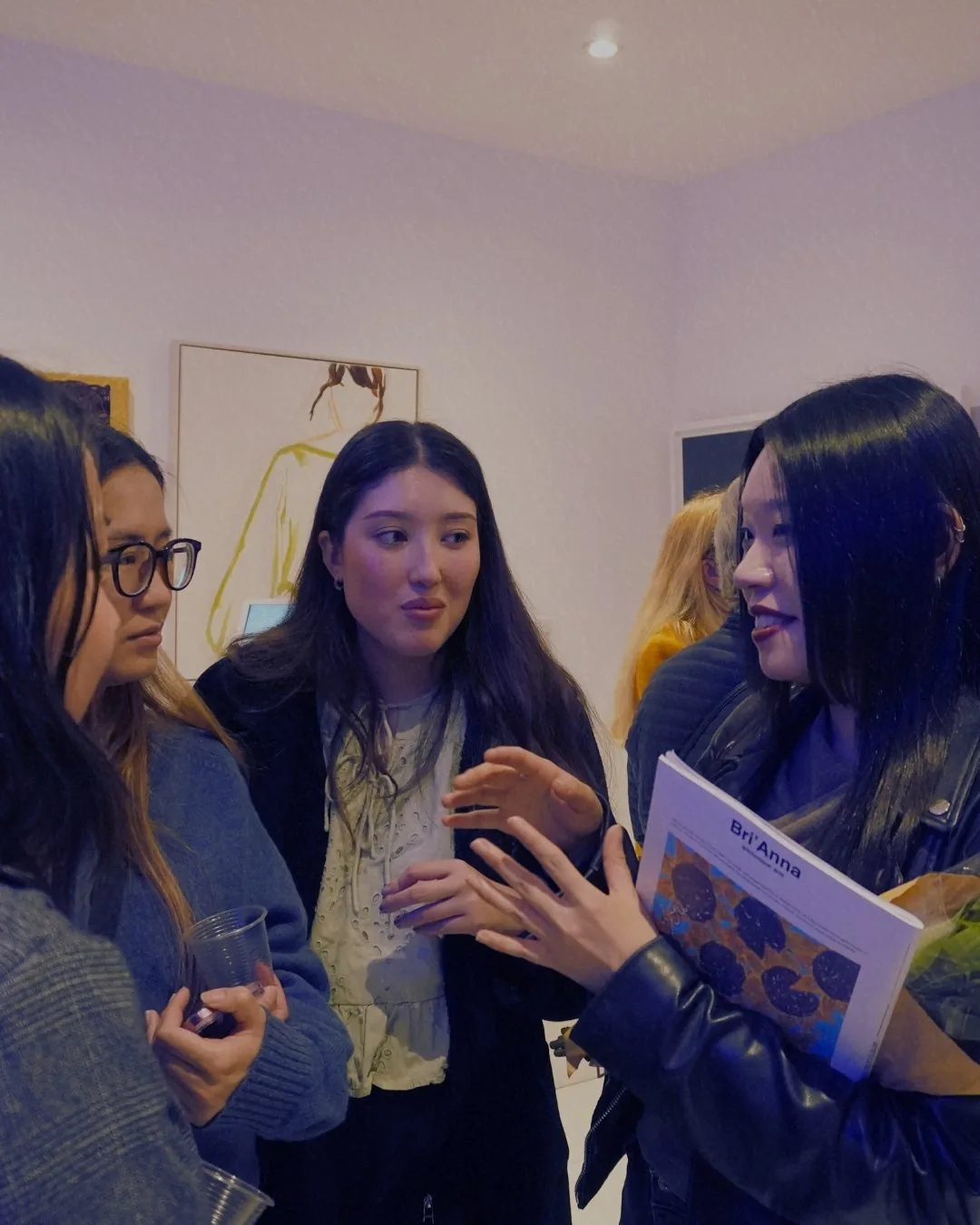 Visitors in conversation, one holding an open magazine.